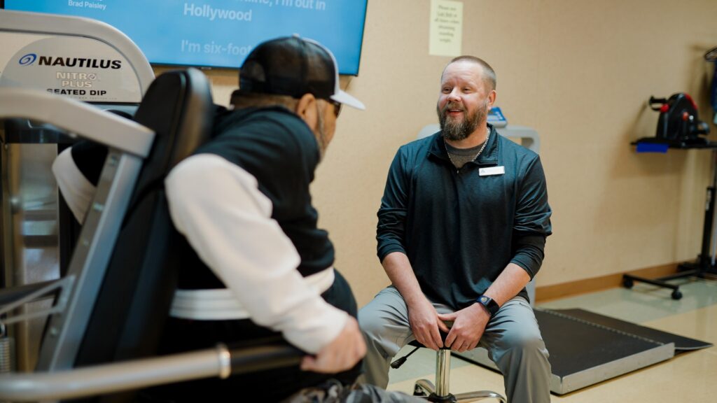 A man in short term rehab physical therapy is assisted by a nurse