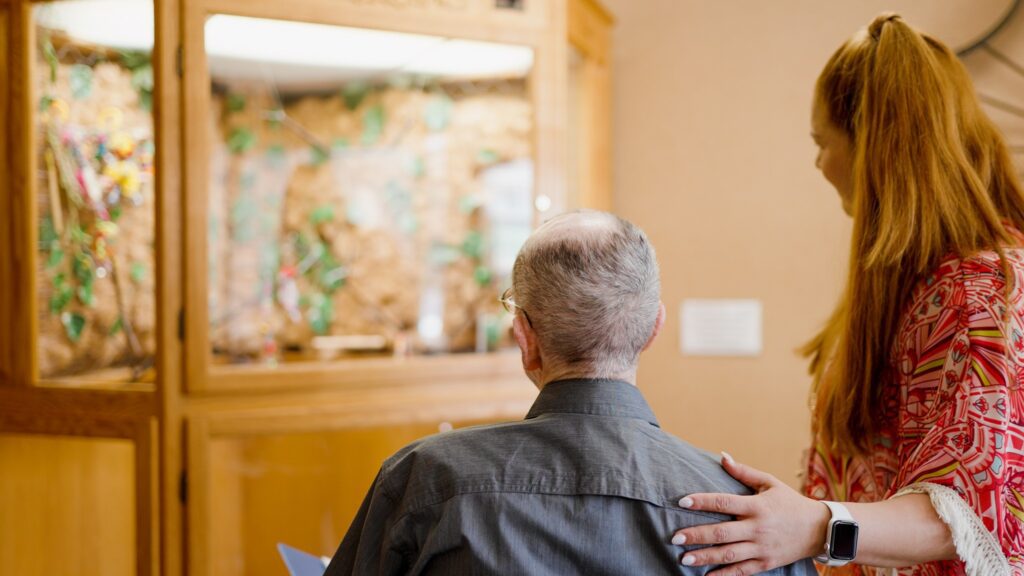 A man and nurse watch a bird at a memory care facility