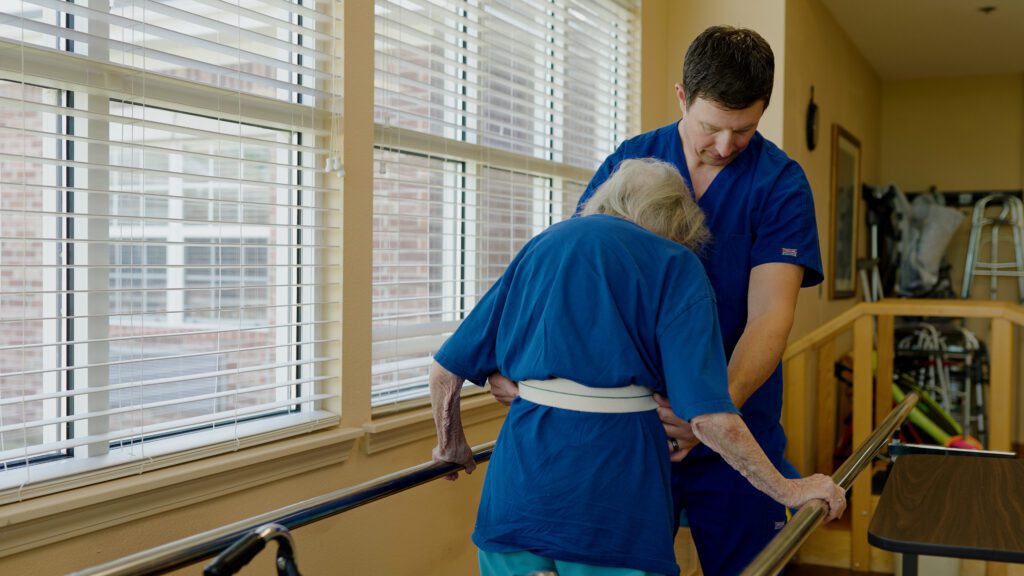 A nurse assists a woman in physical therapy at a skilled nursing facility offering rewarding careers in healthcare